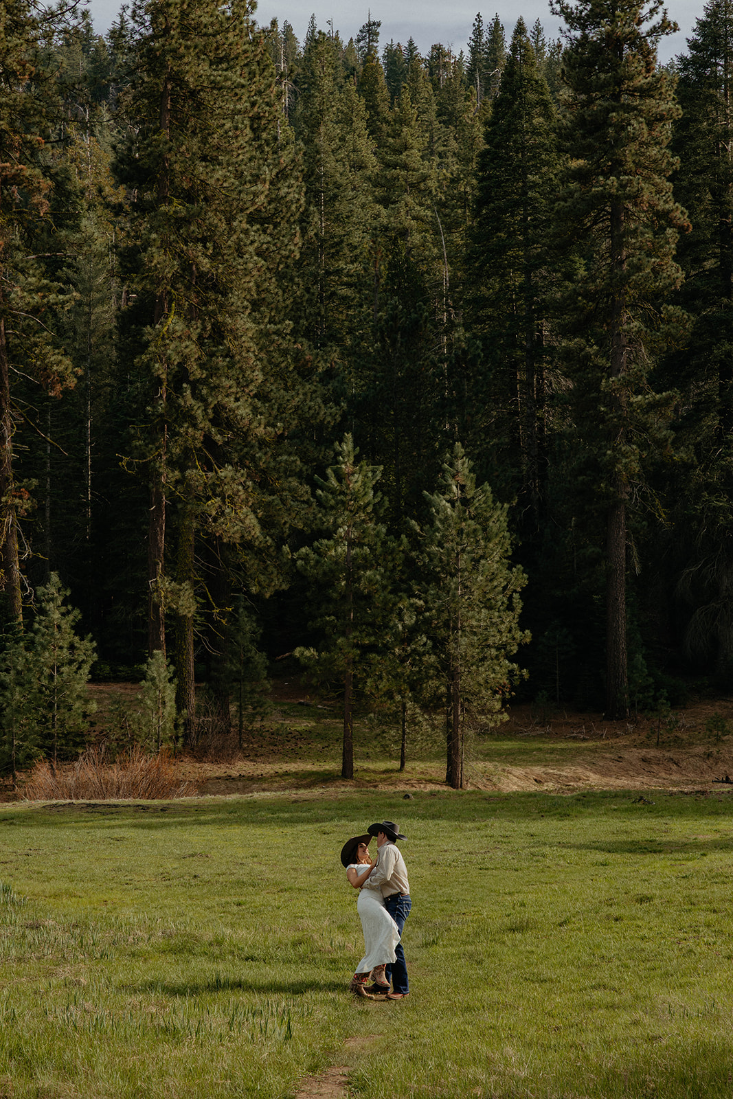 Madalyn and Hunter together beneath tall pine trees